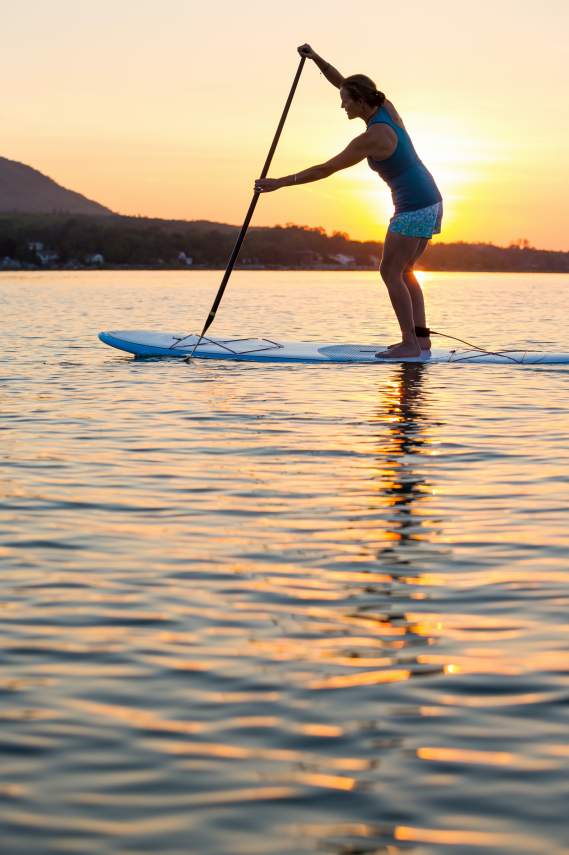 Woman paddle boarding at sunset.
